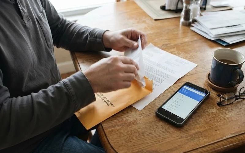 A Florida homeowner reviewing a foreclosure summons and mortgage paperwork at a kitchen table with a laptop nearby